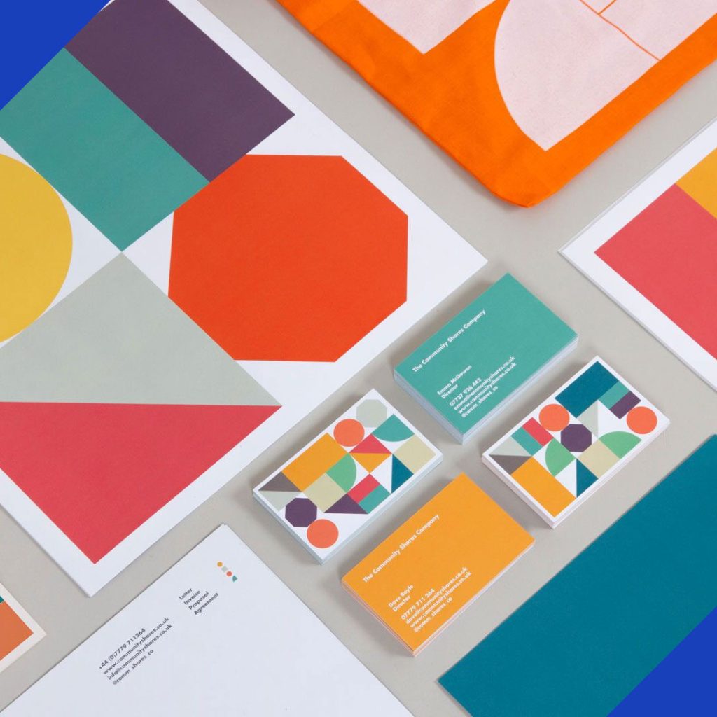 A flat lay of creative branding assets, including business cards, letterhead, and fabric with modern geometric patterns, representing the branding services from JR Digital Media.
