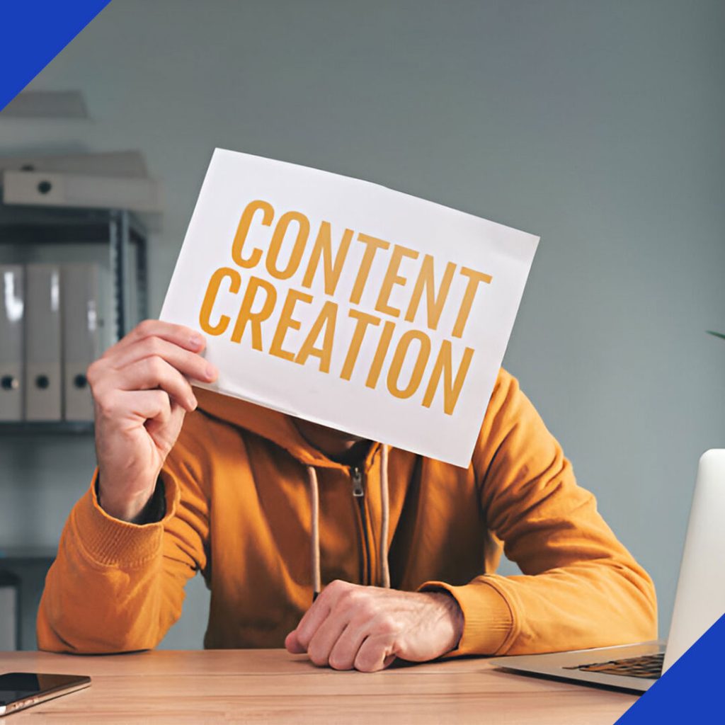 A person at a desk holding a sheet of paper that says "Content Creation," representing the creative services from JR Digital Media.