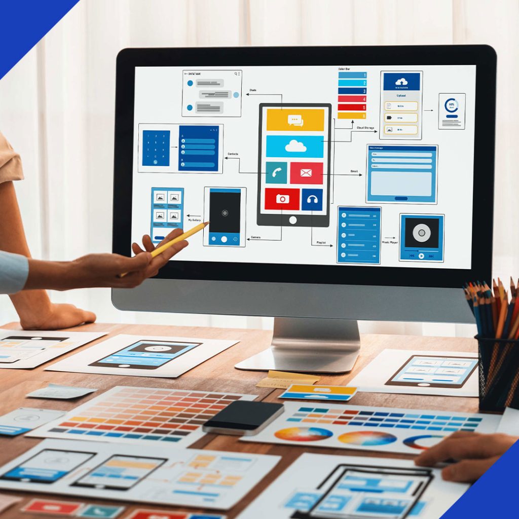 Two people collaborating on a multimedia campaign plan, designing a user interface for various devices on a large computer screen, symbolizing the services from JR Digital Media.