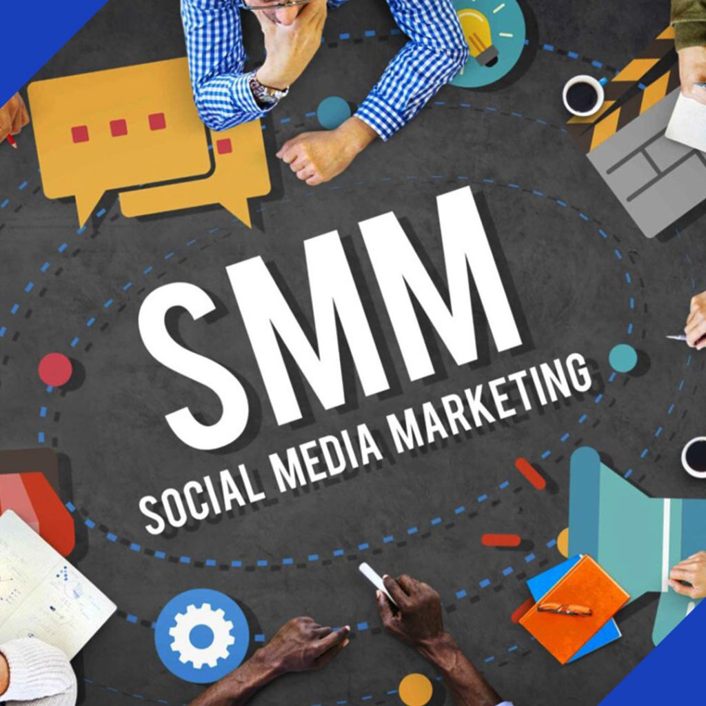 A top-down view of a team collaborating on a social media marketing strategy, with the text "SMM" and "SOCIAL MEDIA MARKETING" on a table, representing the services of JR Digital Media.